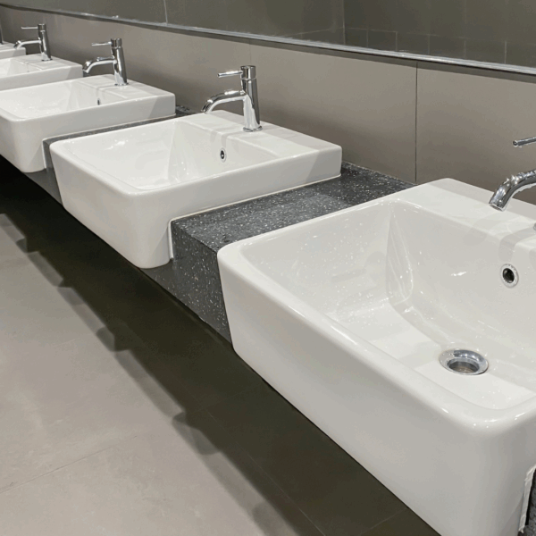 Lavabos alignés avec robinets modernes dans un espace sanitaire collectif.