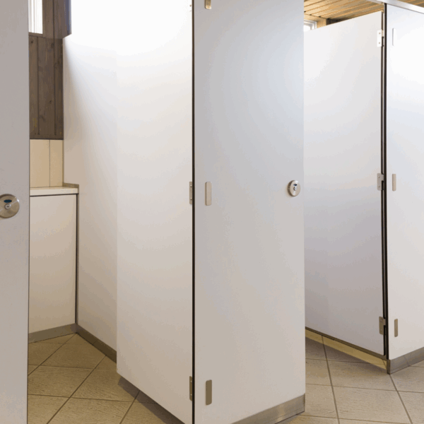 Rangée de cabines de toilettes avec portes fermées dans un espace sanitaire.